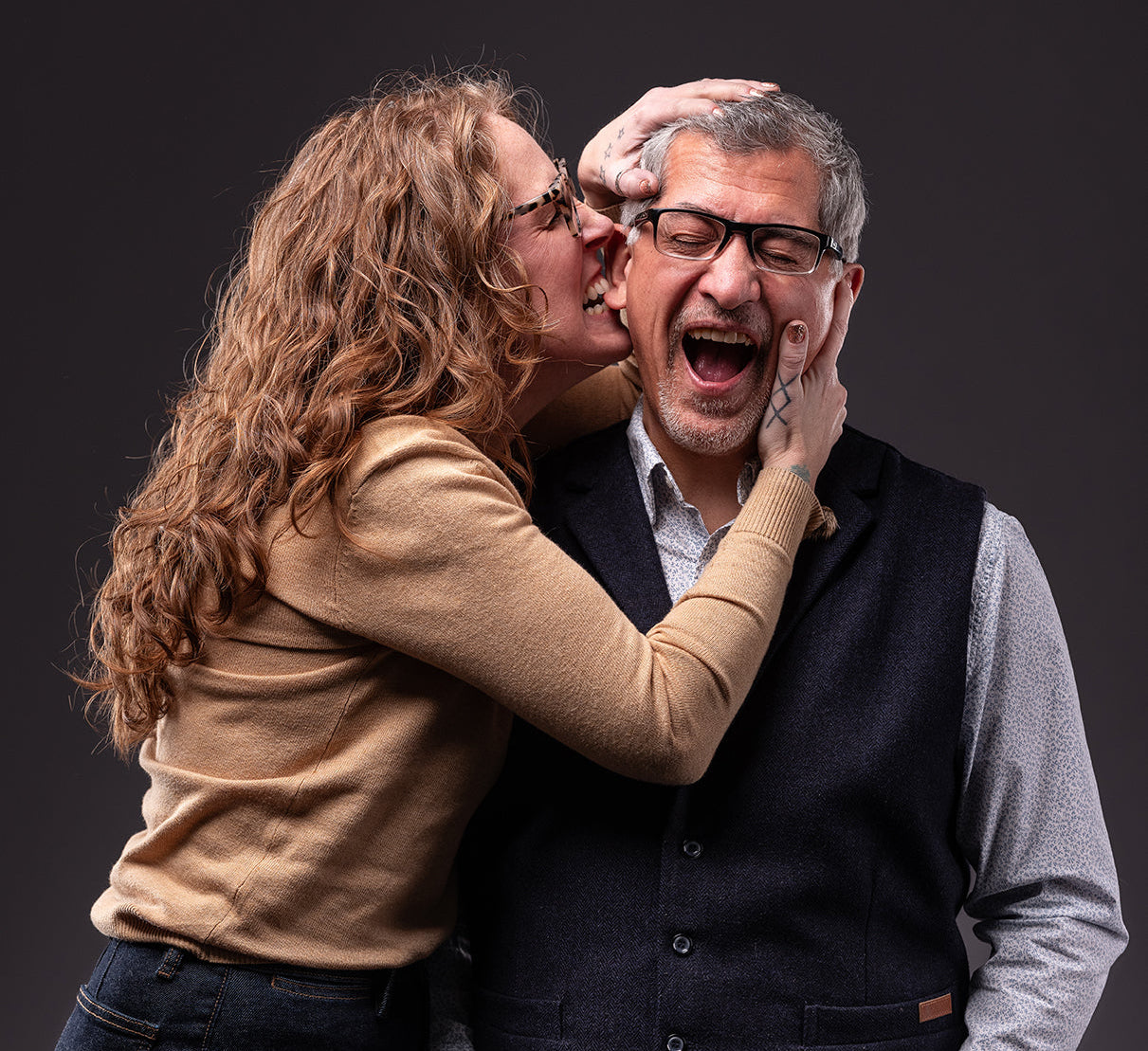 Woman biting a man's ear against a dark background